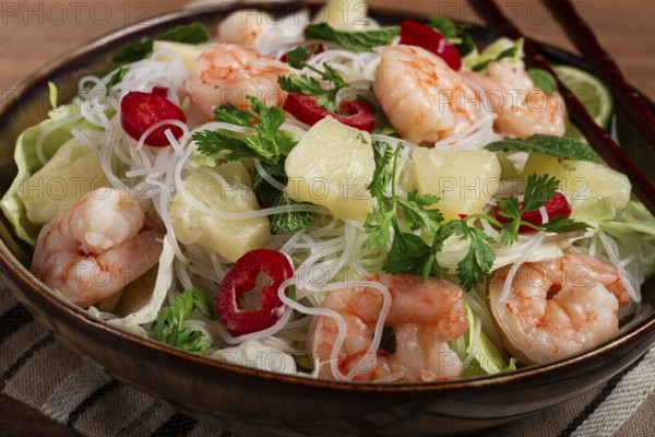 Thai salad with shrimp and rice noodles, pineapple slices, coriander and mint leaves, homemade, no
