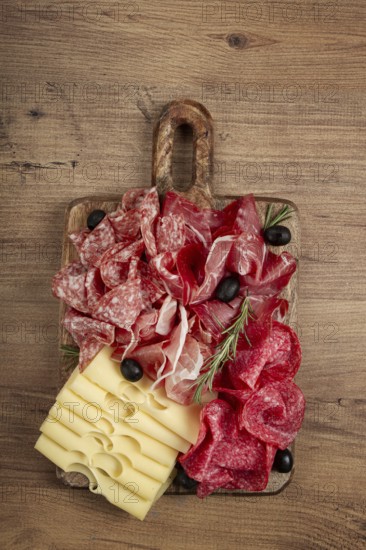 Assorted meat, appetizer, prosciutto, salami and ham, with maasdam cheese and olives, on a wooden