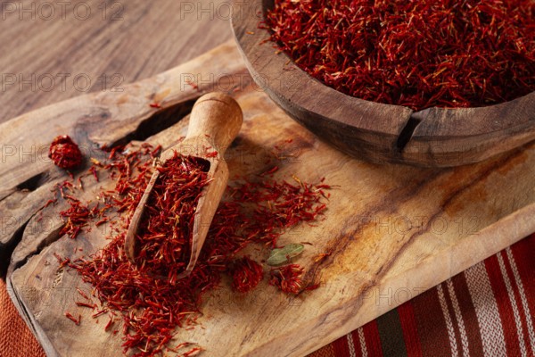 Spice saffron threads, in a wooden bowl, on a wooden table, top view, close-up