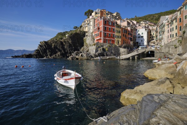 White boat, colorful houses under blue sky, view of the fishing village of Riomaggiore, port,