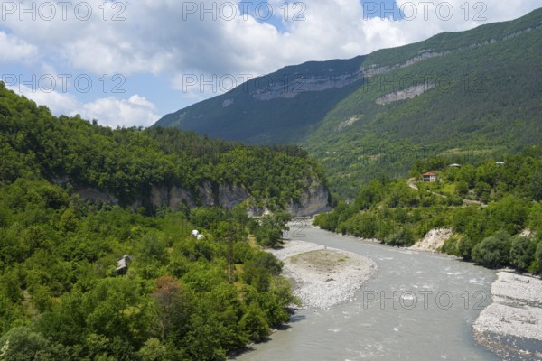 River flows through a wooded valley in the mountains under a cloudy sky, Rioni river near Alpana,