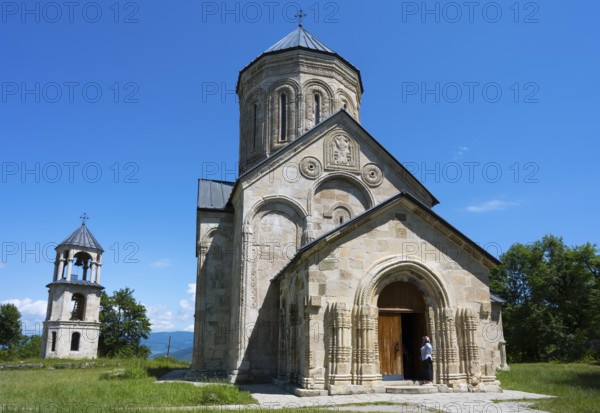 Romanesque church with bell tower in rural area under clear blue sky, Nikorzminda Cathedral,
