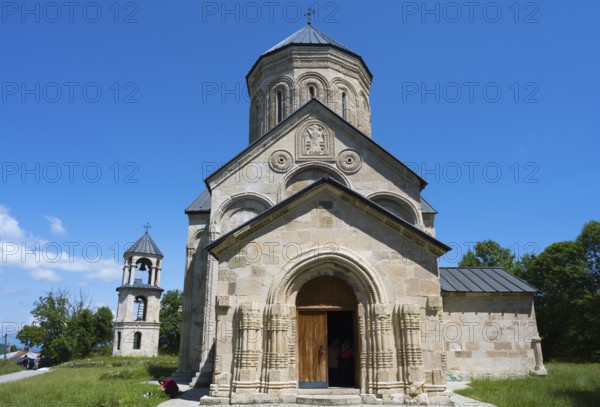 Stone church with detailed façade under clear blue sky, Nikorzminda Cathedral, Nikorzminda
