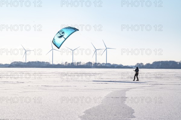 Person kiting on frozen Dümmer Lake, wind turbines in the background, Lembruch, Diepholz district,