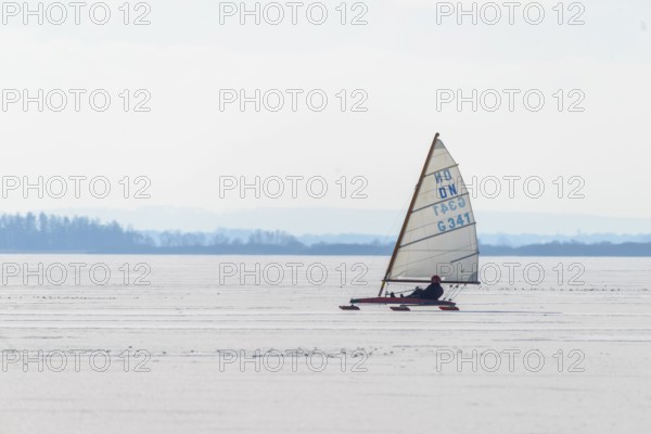 Ice sailor glides over icy surface under clear sky in wintry landscape, Lembruch, Diepholz