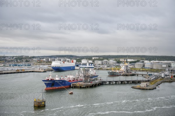 Industrial port with tanks and ships on calm water under a grey sky, Gothenburg, Västra Götalands