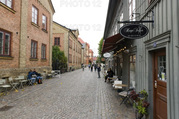 Lively street scene with cafés and historic buildings along a cobblestone street in Gothenburg's