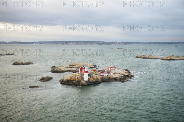 Small rocky island with lighthouse and red buildings in the calm sea, near Gothenburg, Västra
