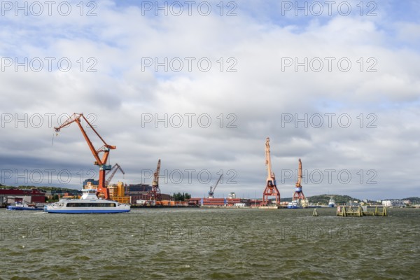 Industrial port on Götaälv in Gothenburg with several large cranes on the riverbank, Gothenburg,