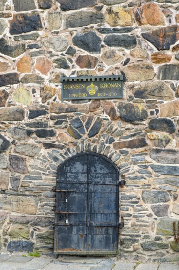 Historic stone wall with a metal door and a sign about Skansen Kronan, detail of an old stone wall