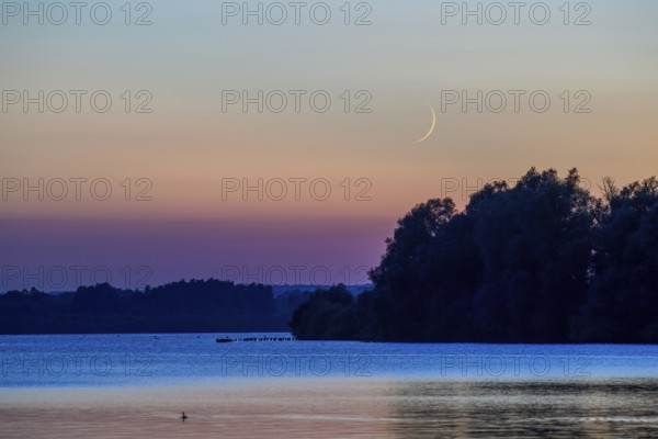Delicate crescent moon over quiet Dümmer Lake late in the evening at sunset, Lembruch, Dümmer See,