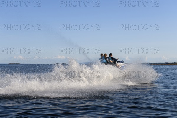 People ride fast across Lake Vänern on a jet ski and generate waves, Värmlandsnäs peninsula,