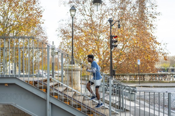 Man actively training by running up a metal staircase in a parisian urban setting, performing