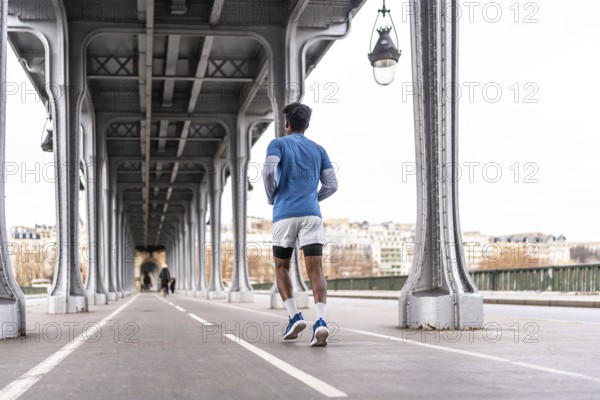 Man is jogging on a bridge in paris, focusing on urban fitness and a healthy lifestyle in the