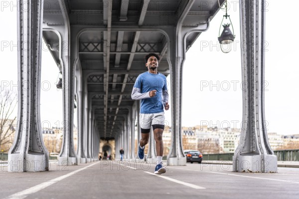 Young man smiling and running along the bir hakeim bridge in paris, engaging in urban sport and