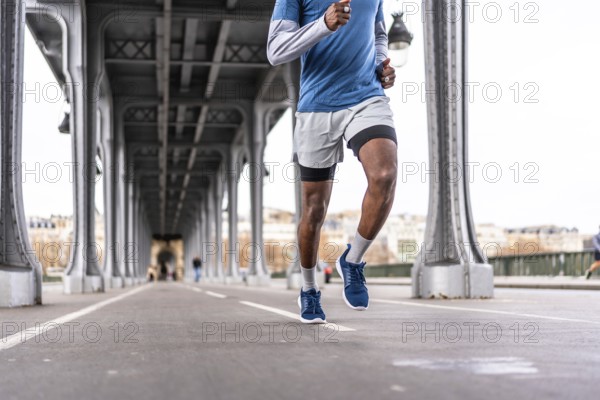 Young man running a daily urban workout across bir hakeim bridge in paris, showcasing fitness,
