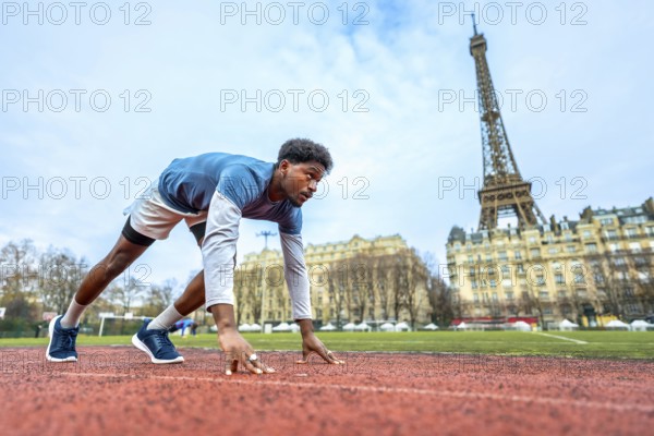 Young male athlete getting ready to run on an outdoor track in the heart of paris, focusing on the