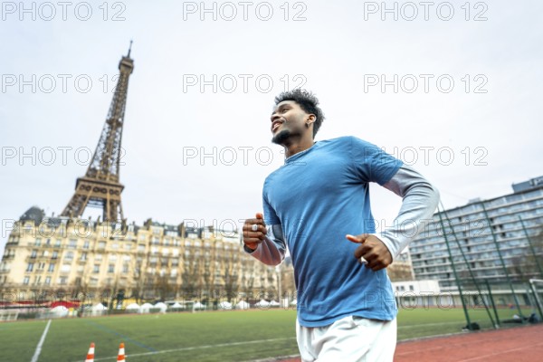 Young athletic black man training on a running track with the iconic eiffel tower and parisian