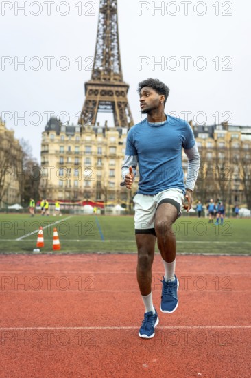 Young man doing speed drills on an outdoor running track, practicing high knees in paris with the