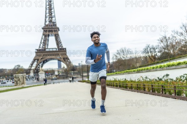 Young athletic black man jogging along paris streets, training outdoors near the eiffel tower,