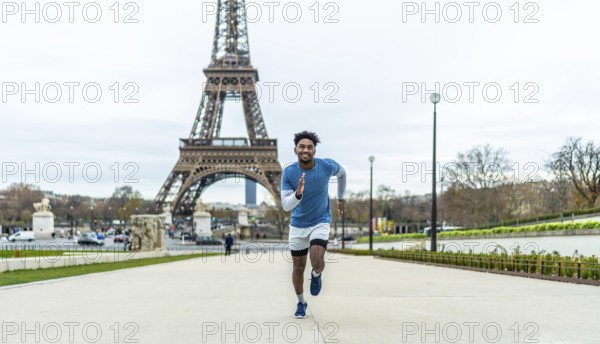 Young man actively running outdoors in front of the eiffel tower, symbolizing fitness, health, and