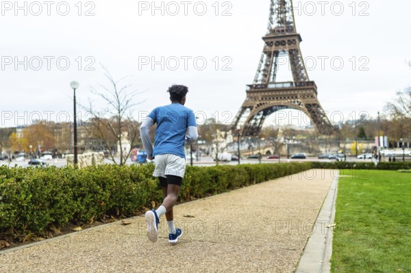 Young man exercising outdoors on a gravel path in paris, enjoying a fitness run with the iconic