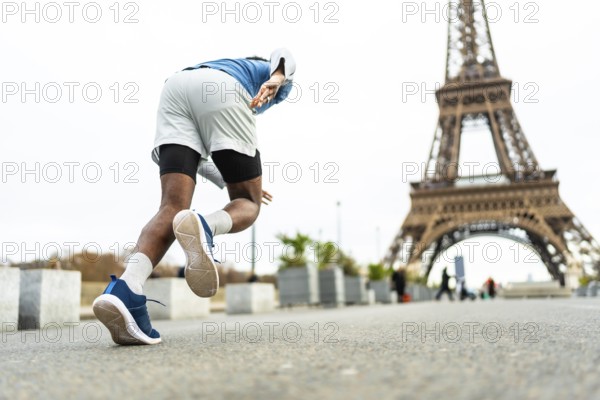 Male athlete starting to run in paris, training near the eiffel tower, symbolizing endurance,