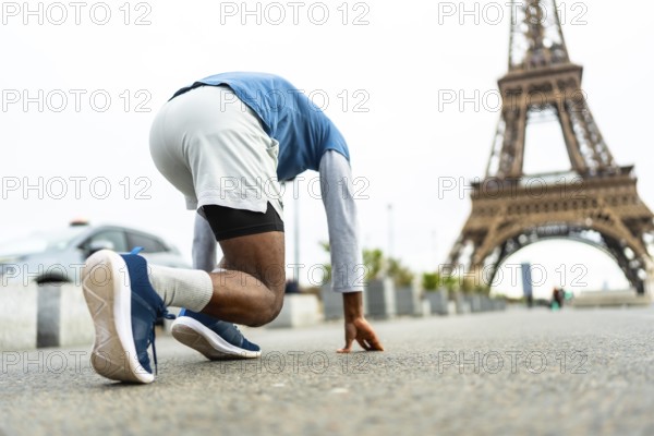 Athlete in starting position, poised for a run on an urban street, training for speed and