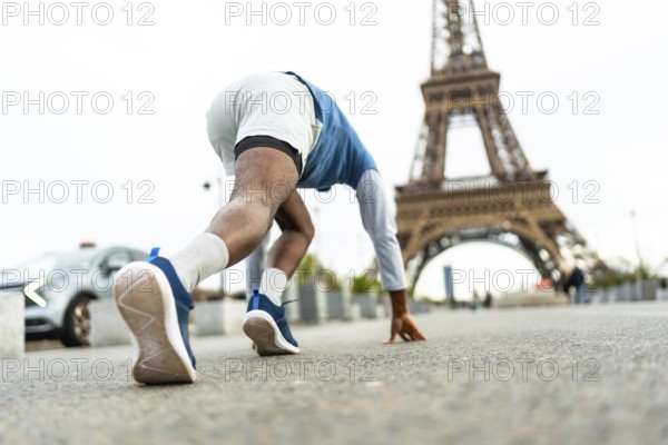 Male athlete in starting block position preparing for a sprint on a city street, with the iconic