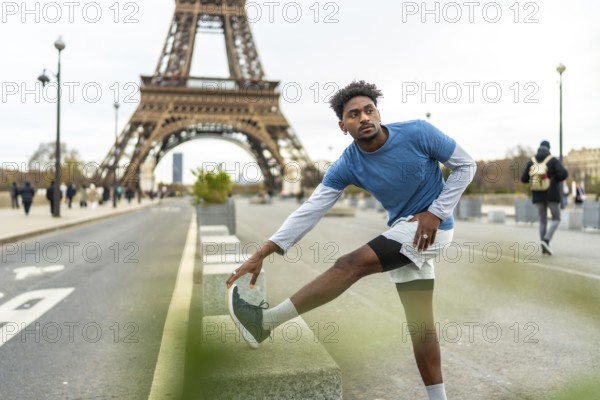 Young athletic man stretching his leg on a low wall, preparing for a workout session with the