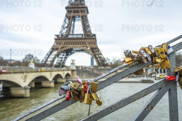 Many padlocks symbolizing everlasting love are attached to a bridge railing, with the iconic eiffel