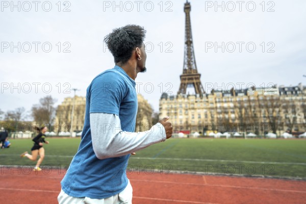 Young man training on a running track with the iconic eiffel tower and parisian buildings in the