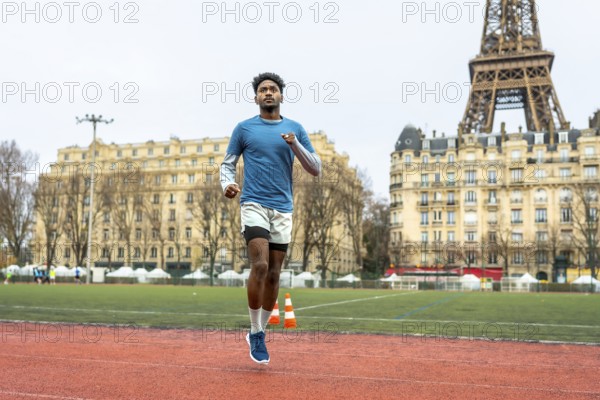 Young athletic man running on an outdoor track in paris, focusing on urban sport performance and