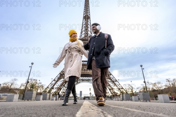 Diverse couple walking outdoors in paris holding hands, enjoying a romantic trip together on a