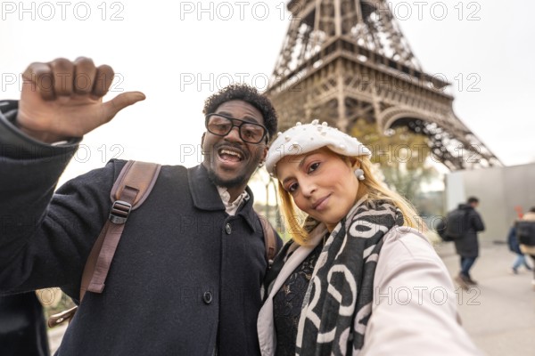 Happy diverse couple smiling into the camera while taking a selfie in front of the eiffel tower,