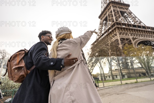 Young diverse couple traveling together, smiling and pointing out a landmark while visiting the