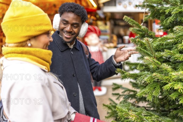 Smiling man pointing at a christmas tree while engaging in conversation with his partner at a
