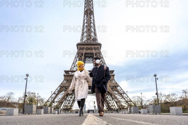 Young diverse couple walking and smiling together in front of the eiffel tower, embracing romance,