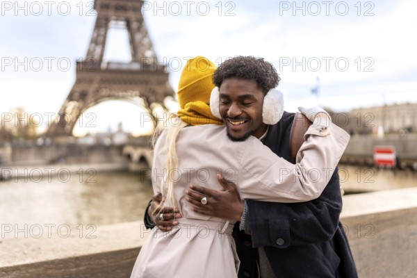 Happy young diverse couple hugging and smiling on a cold paris day, sharing warmth and romance with