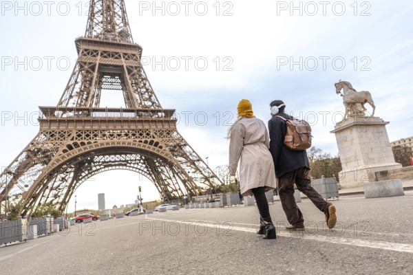 Young couple walking on a street, seen from behind, enjoying a romantic trip to the eiffel tower,