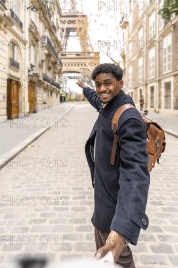 Happy black man leading someone by the hand down a cobblestone paris street, smiling and pointing