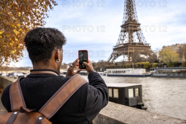 Traveler capturing a moment on smartphone while visiting the iconic eiffel tower in paris, engaging