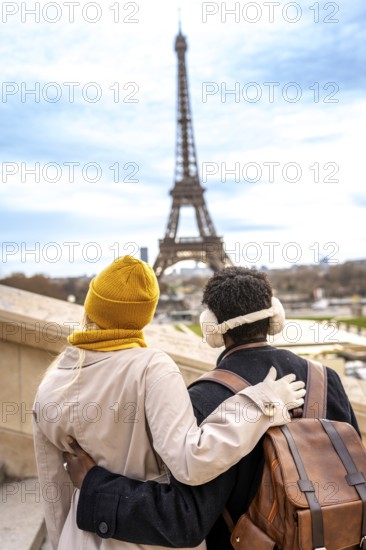 Loving couple standing with arms around each other, enjoying the view of the iconic eiffel tower in