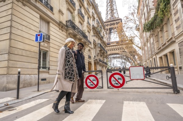 Diverse couple happily walking across a pedestrian crosswalk in a charming european street during
