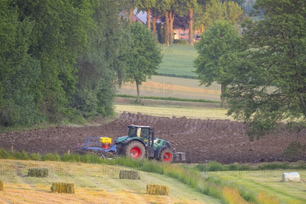 Tractor plows the field in an idyllic rural landscape, Osnabrücker Land, Lower Saxony, Germany