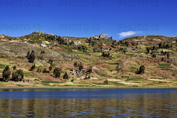 Wide fields stretch across rolling hills overlooking a lake, countryside and farmhouses on Taquile