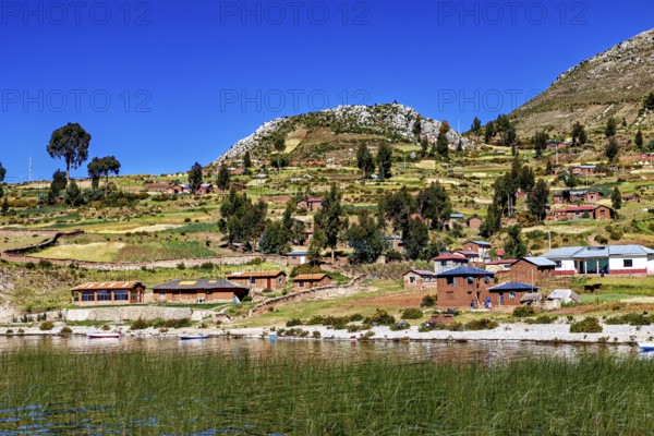 Idyllic village with lakeside farm houses and fields under blue skies, the countryside and