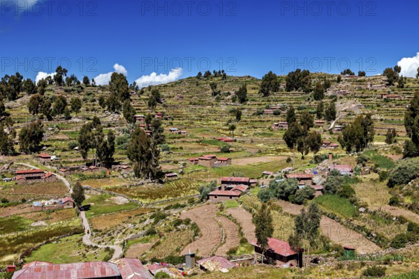 Terraced fields and farm houses stretch across green hills under blue skies, the countryside and