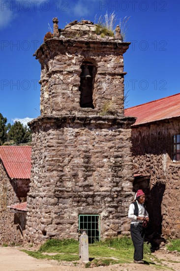 Stony church tower with red roof and a man wearing traditional clothes next to it, The knitting men