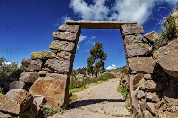 Rectangular stone archway with visible path below, blue sky in the background, stone gates on